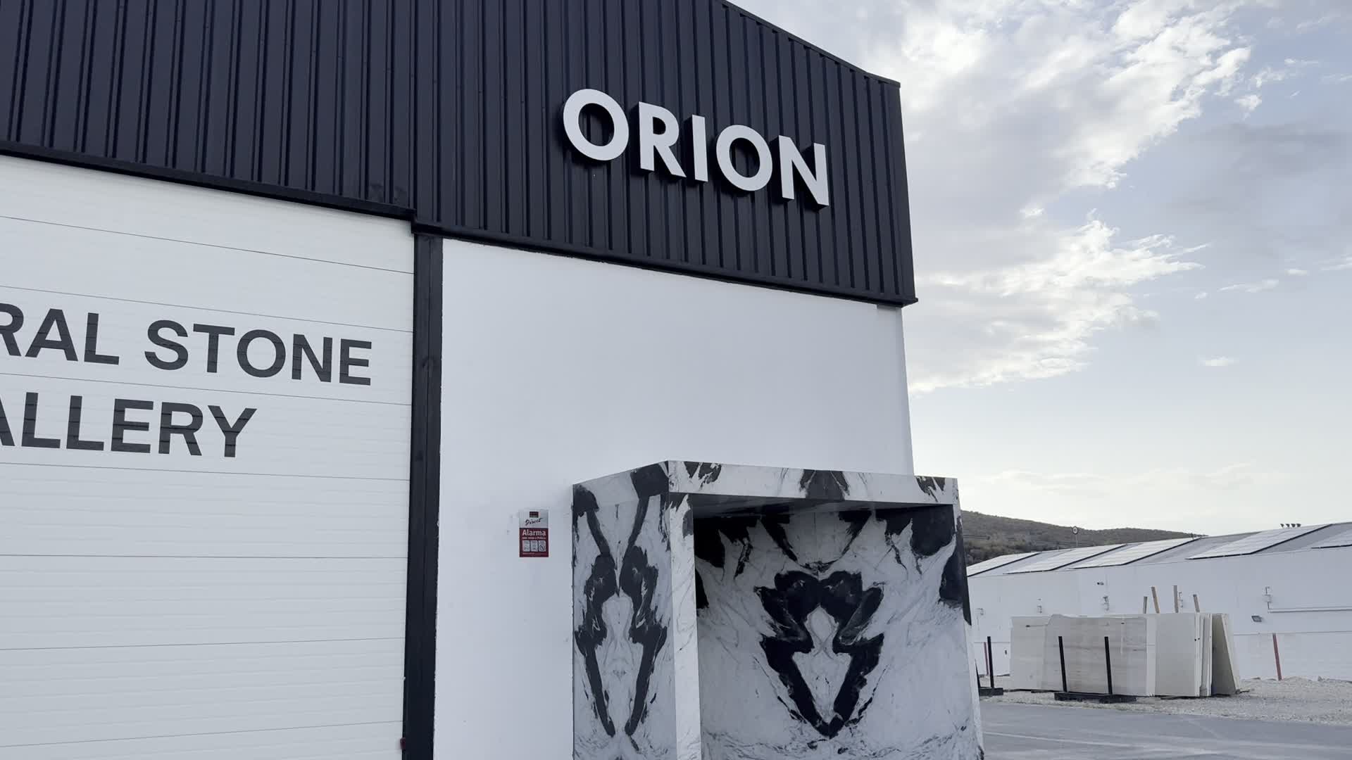 La nave de Orion Stone Group en Macael, con bloques de mármol a la entrada y la sierra al fondo.
