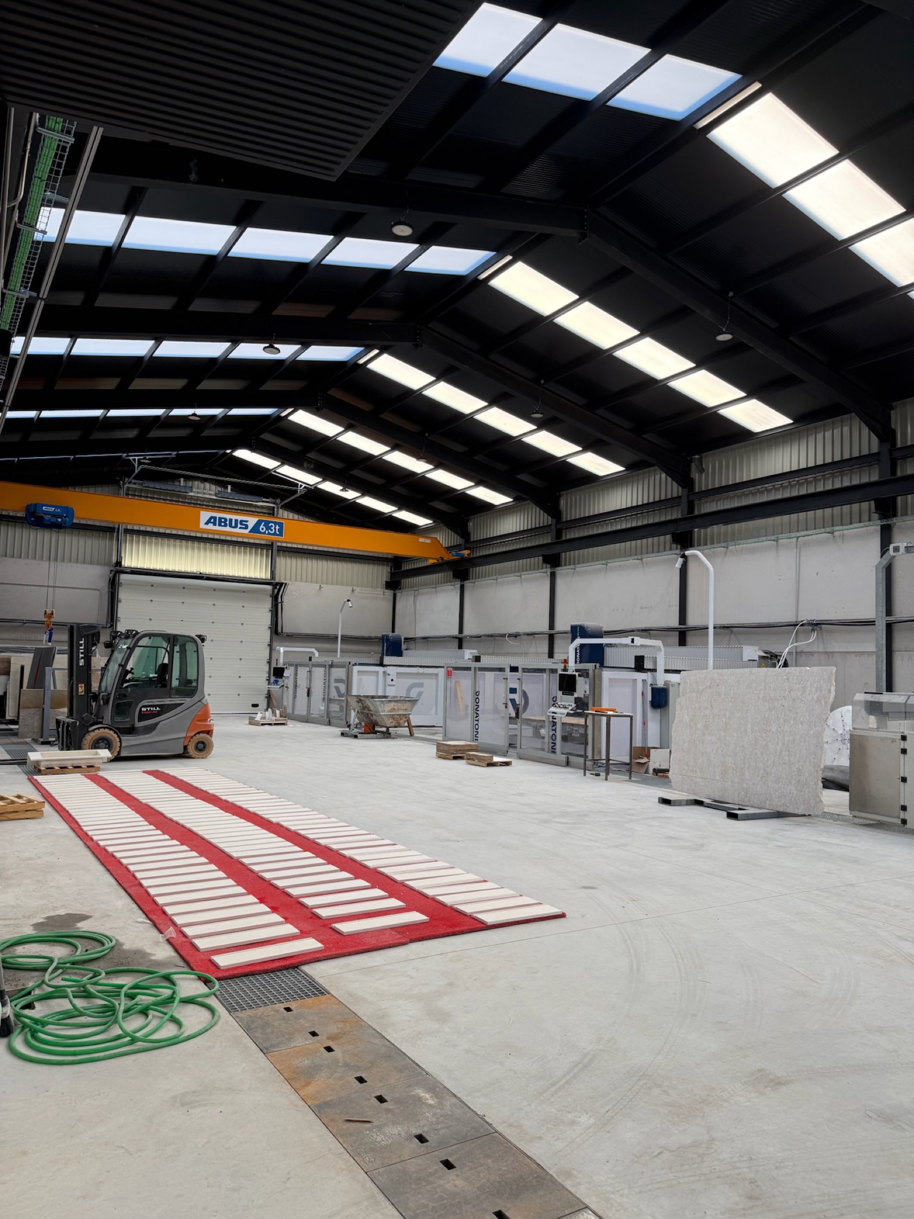 La nave de Orion Stone Group en Macael: tablas de piedra en bastidores bajo el puente grúa.